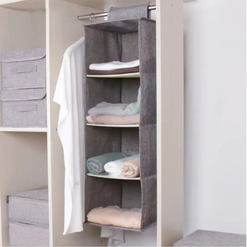 Closet organizer with folded clothes inside a wardrobe.