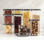 Set of clear storage containers with various food items on a white surface.
