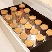 Spice jars with wooden lids organized in a drawer.