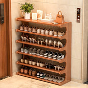 Wooden shoe rack with various shoes on shelves in a room setting.