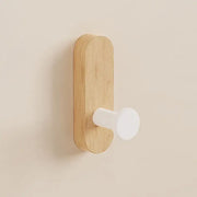 Wooden wall hook with a white ceramic knob on a beige background