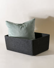 Gray storage basket with a light blue pillow on a white background