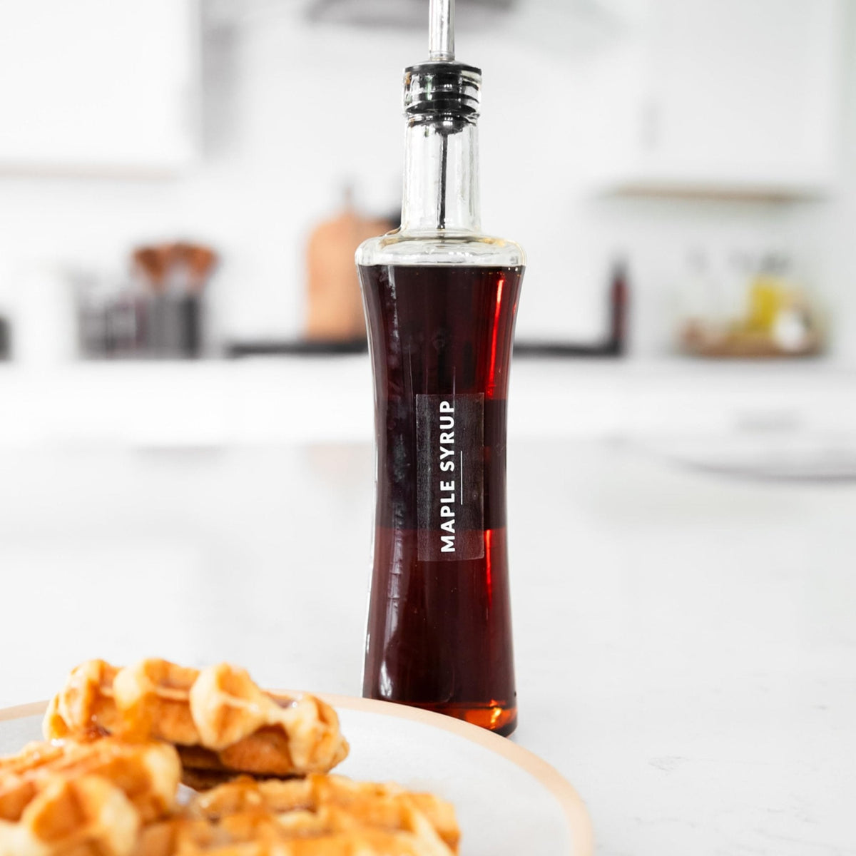 Bottle of maple syrup on a plate with waffles in a kitchen setting