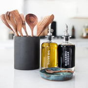 Olive oil and balsamic vinegar bottles with wooden spoons in a kitchen setting