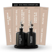 Black oil and vinegar bottles with labels in front of a set of oil and vinegar label sheets.